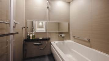 Un baño moderno con bañera, ducha, tocador con espejo y artículos de aseo.