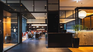 Un hall d’hôtel moderne comprenant un comptoir d’accueil, un espace salon et un bar.