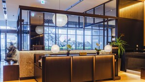 Un comptoir d’accueil avec une pancarte indiquant « Concierge », de grandes fenêtres et une vue sur un espace extérieur rocheux.