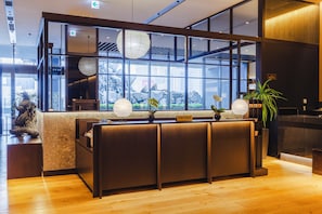 A reception desk with a 'Concierge' sign, large windows, and a view of a rocky outdoor area. - Hotel Gracery Shinjuku (Tokyo)