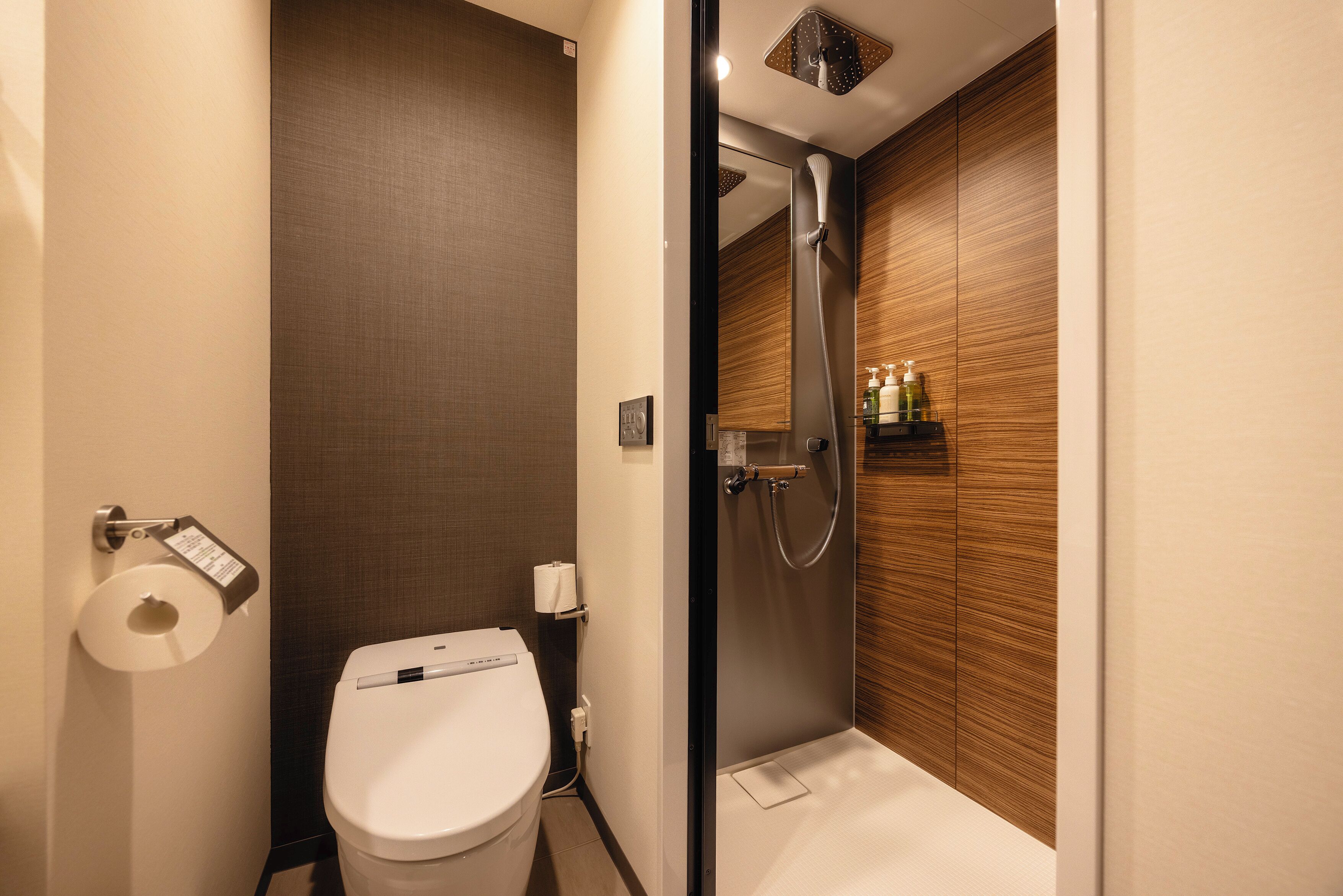 A modern bathroom with a toilet, a shower, and a wooden wall.