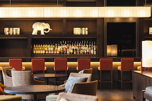 A bar area with seating, bookshelves, and a variety of bottles.