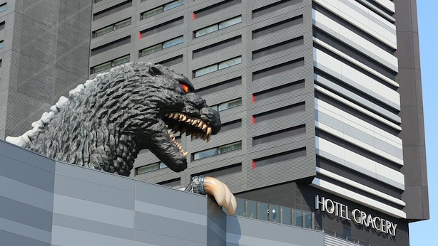 Un bâtiment dont la façade est ornée d’une grande sculpture de dinosaure très réaliste.