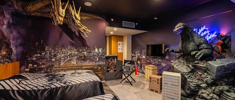 A hotel room with a bed, a cityscape mural, a large dragon decoration, and a Godzilla figure.