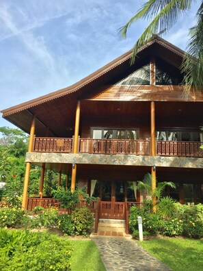 A two-story building with a balcony, surrounded by lush greenery and a stone pathway leading to the entrance. - Baan Laem Noi Villa (Koh Samui)