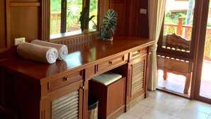 Un mueble de baño de madera con un espejo grande, un perchero y una ventana con vistas a la vegetación.