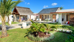 A resort with a pool, outdoor seating, and tropical landscaping. - Clos du Littoral by Fine and Country (Grand-Baie)