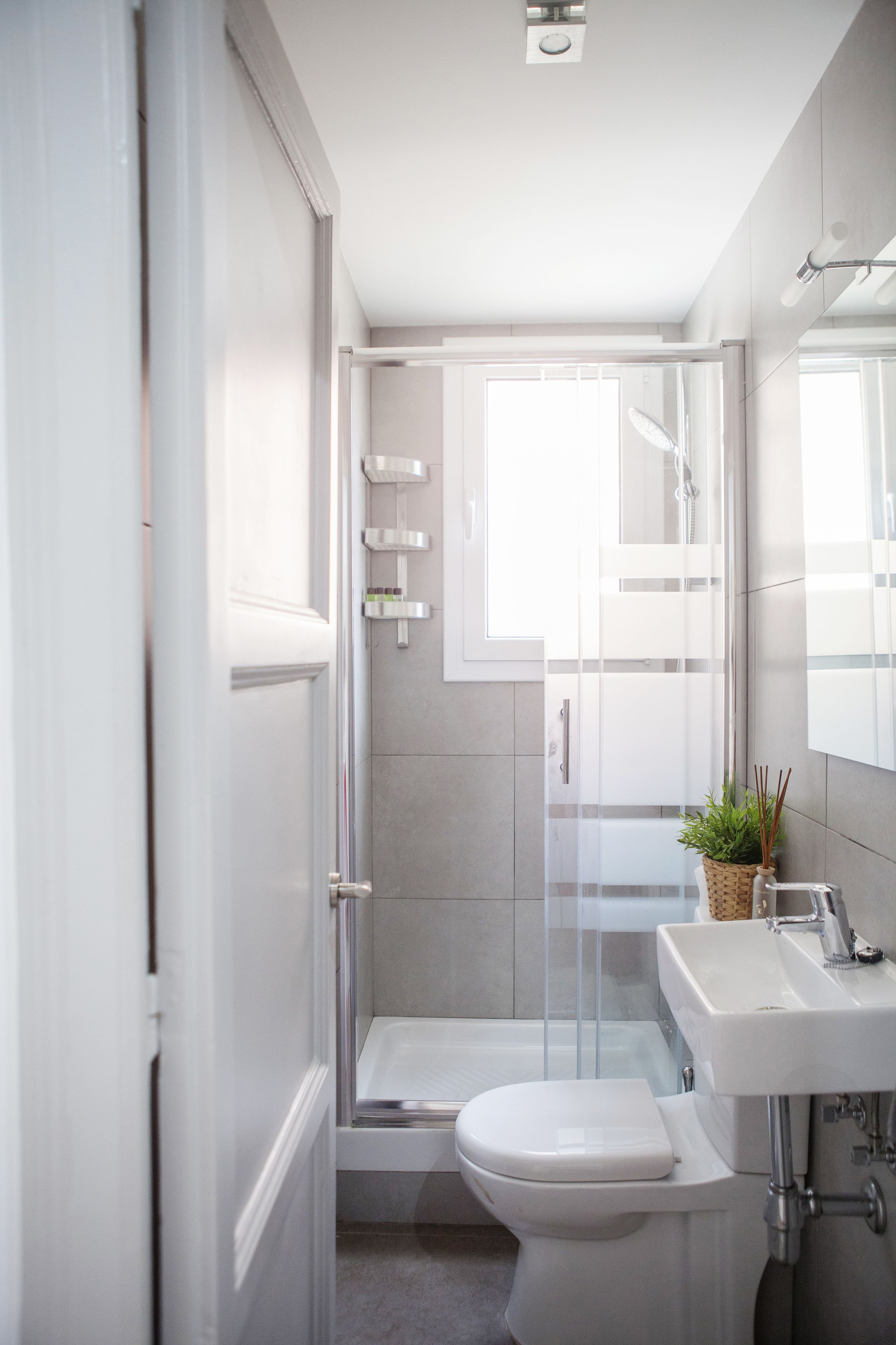 A modern bathroom with a glass shower enclosure, a white toilet, and a sink.