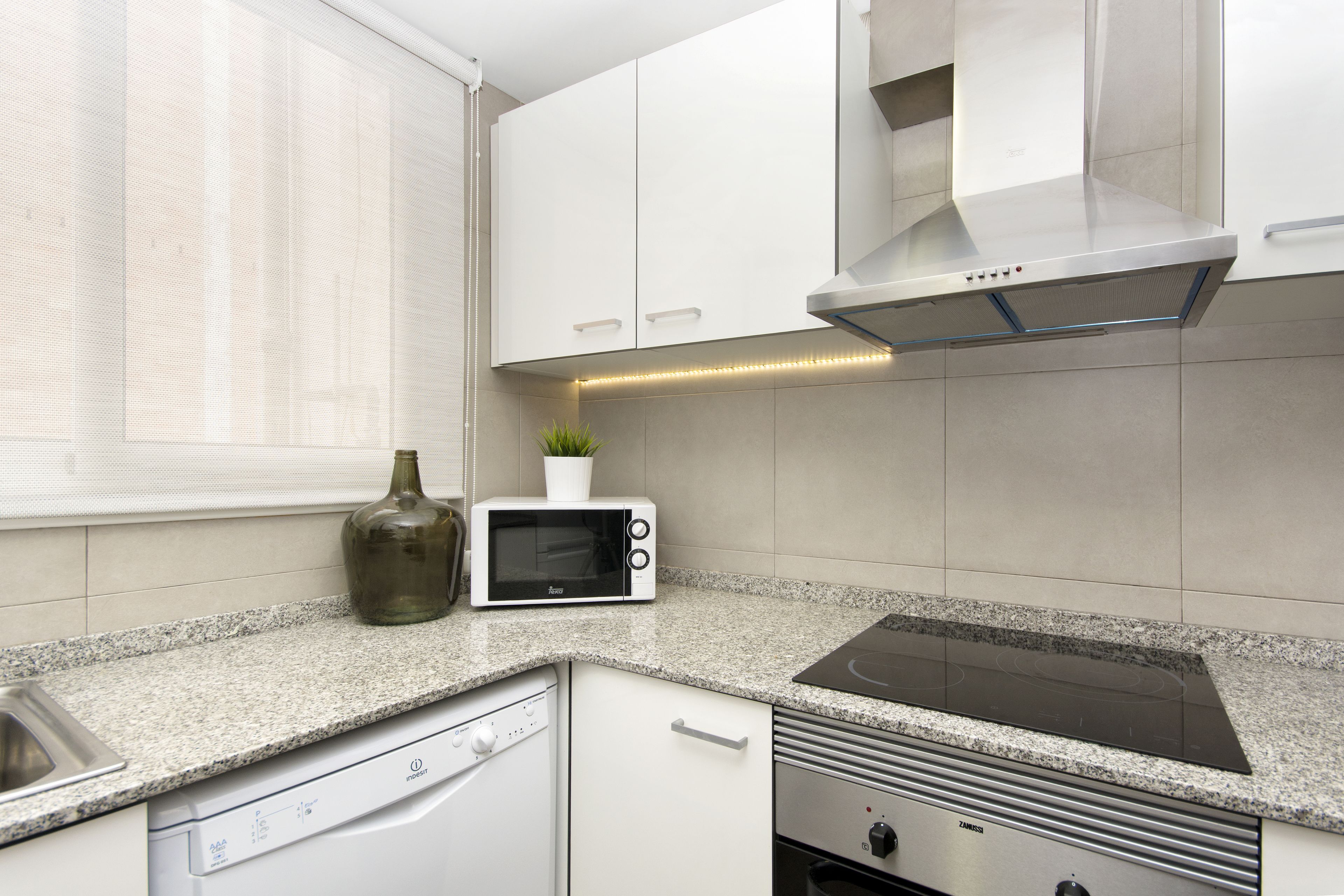 A modern kitchen with white cabinets, a built-in microwave, a dishwasher, and a stove.