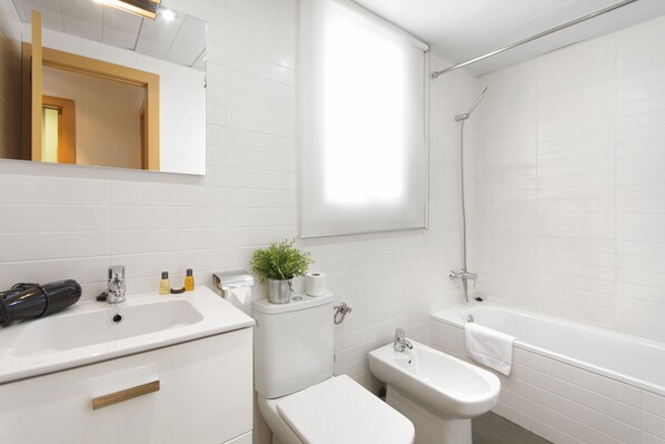 Une salle de bain moderne équipée d’un lavabo, de toilettes, d’un bidet et d’une baignoire.