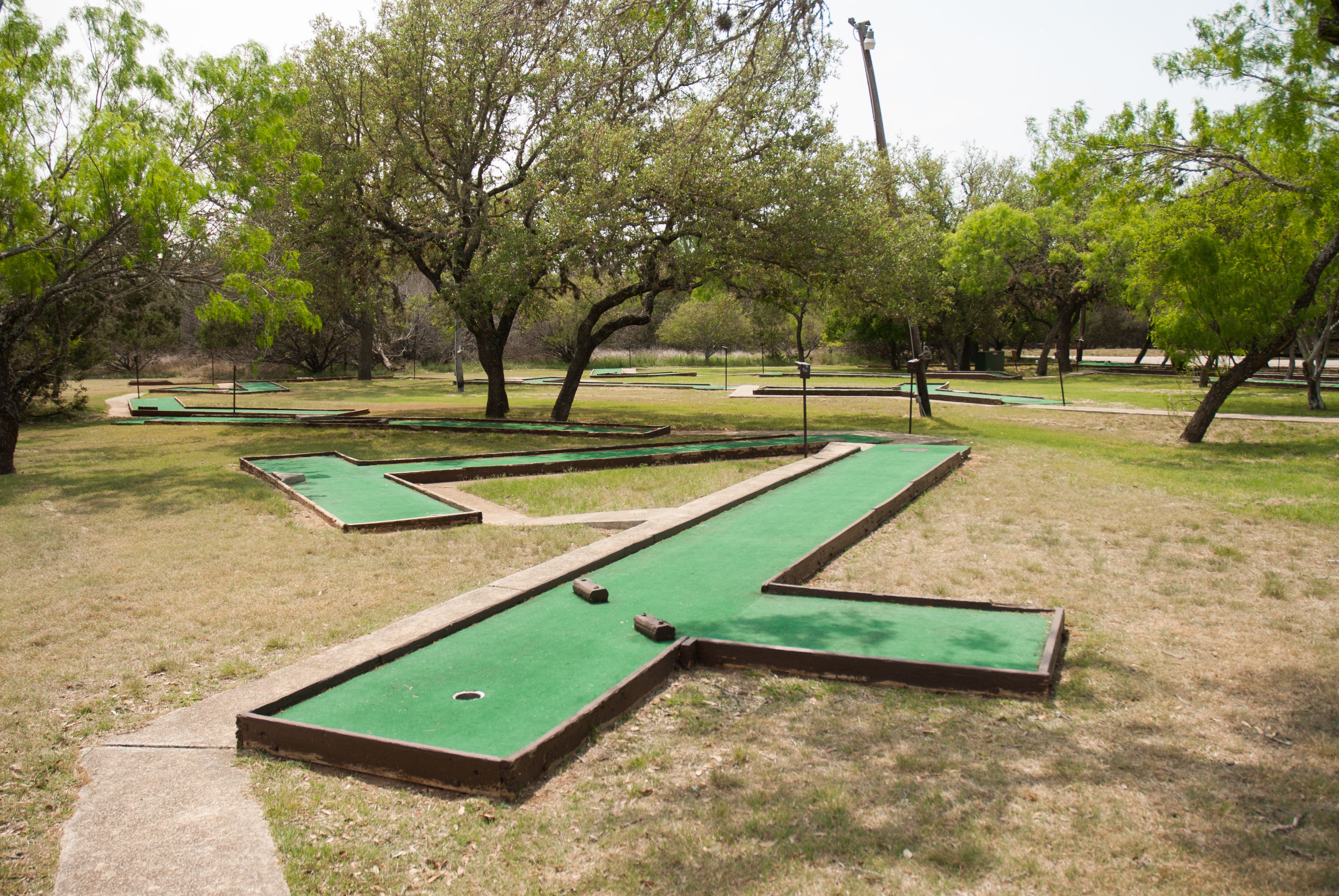 A miniature golf course with multiple green putting areas and a clear path between them.