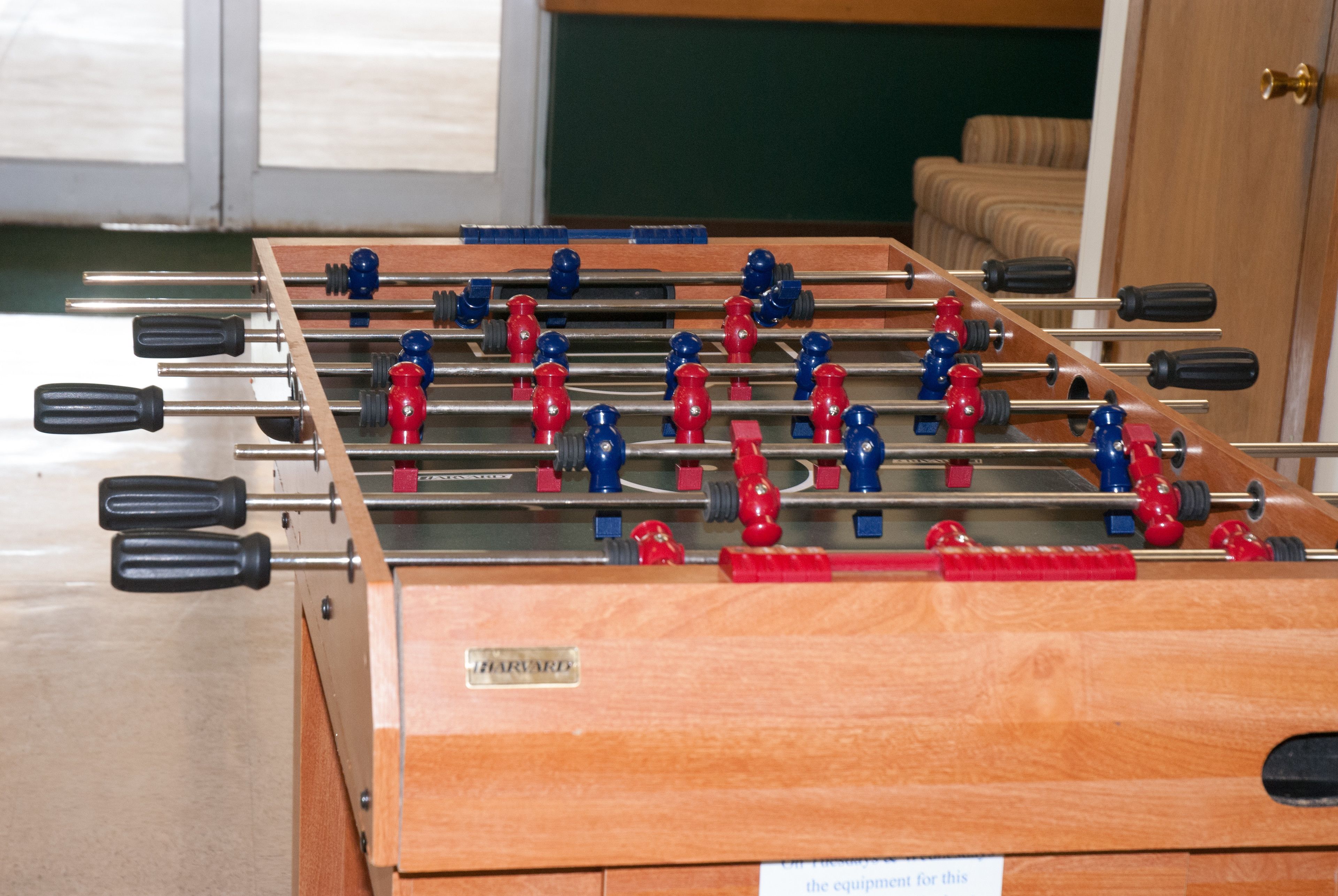 A foosball table with a wooden base and metal rods, labeled "HARVARD."