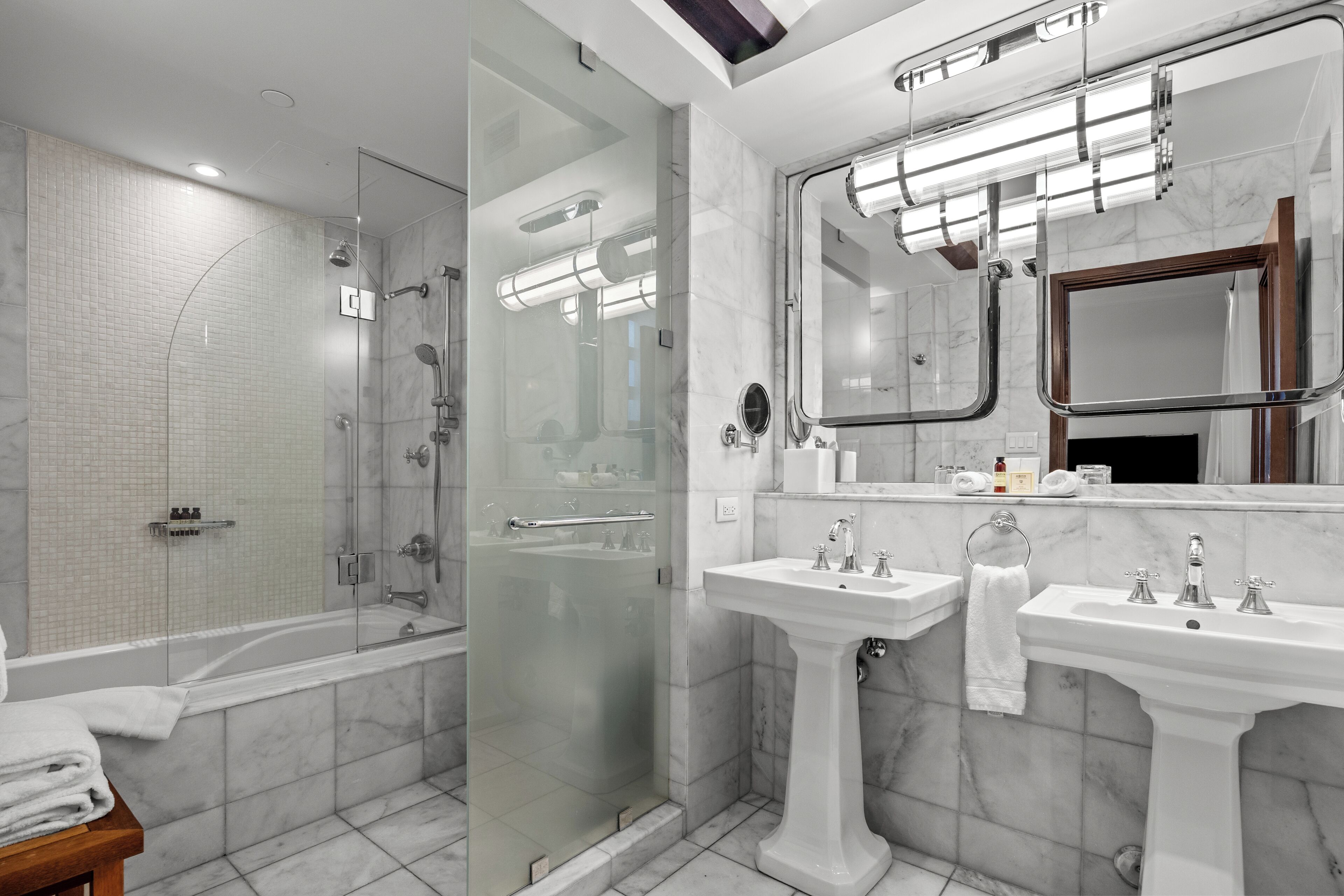 A modern bathroom with a glass-enclosed shower, two sinks, and a large mirror.