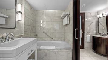 A modern bathroom with a double sink, a bathtub, and a large mirror.