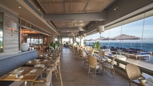 A spacious outdoor dining area with wicker chairs and tables, overlooking the ocean.
