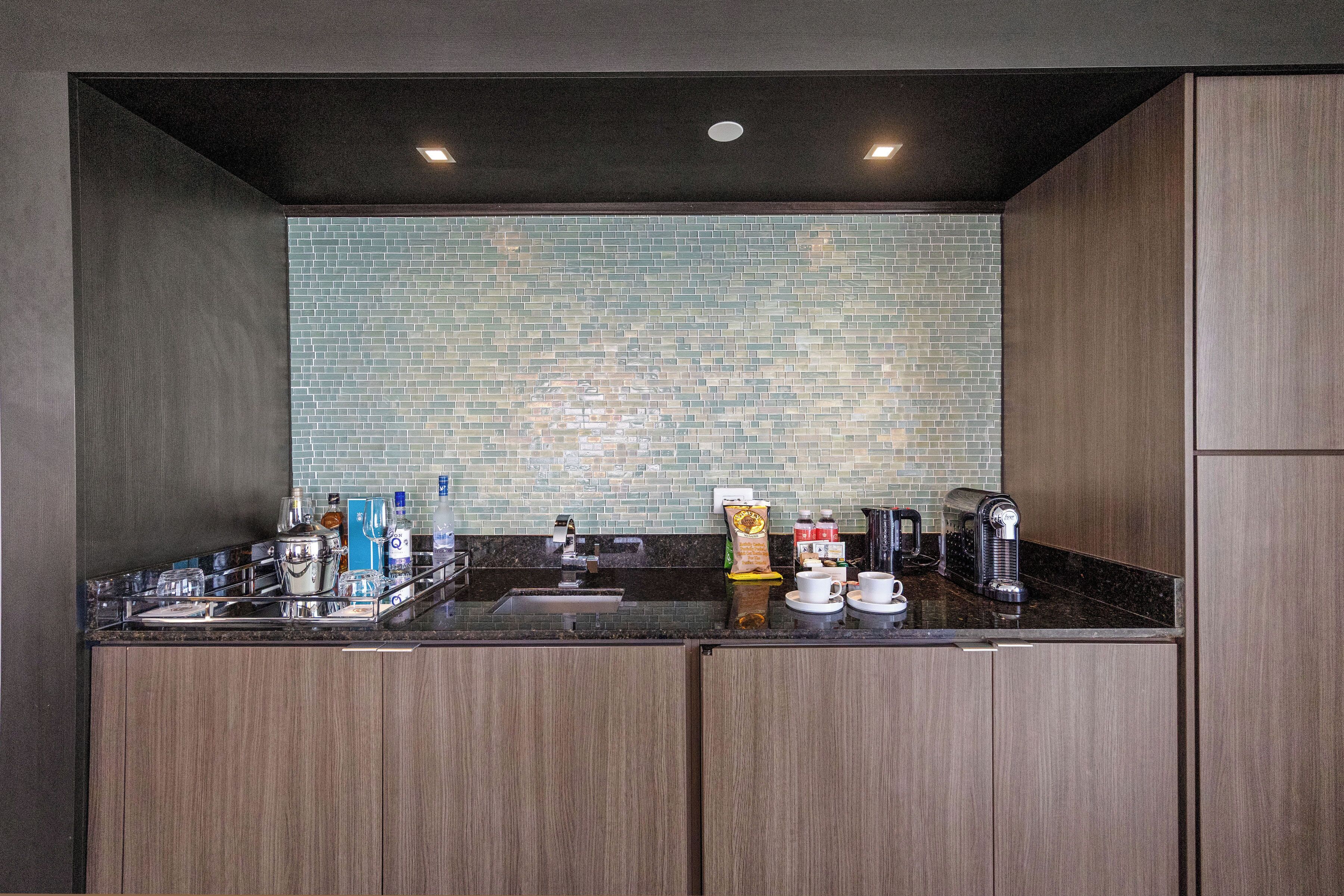 A modern kitchen with dark wood cabinets, a black countertop, and a tiled backsplash.