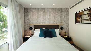 A modern hotel room with a large bed, a wooden accent wall, and a painting on the wall.