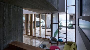 A modern interior with a wooden bench, a green sofa, and a large window offering a view of the outdoors.