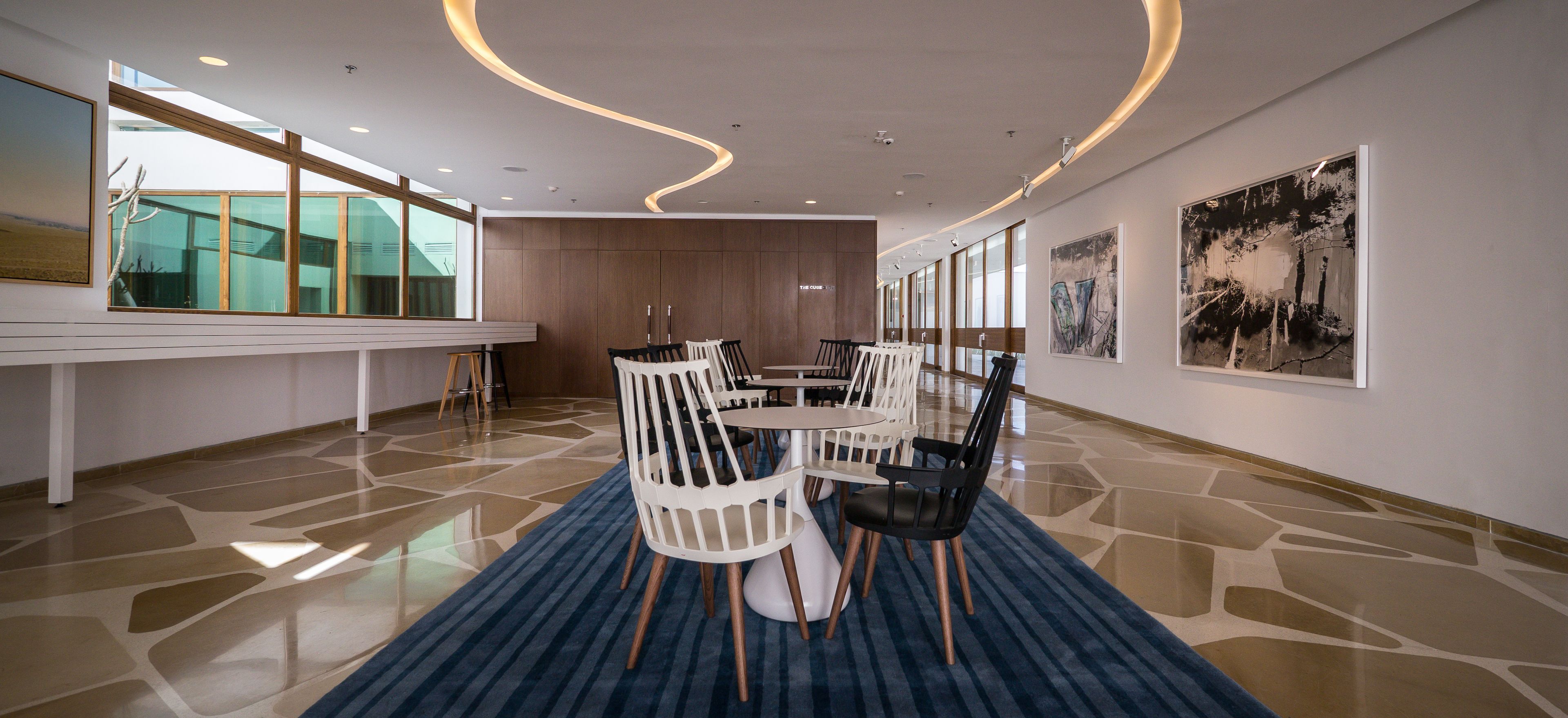 A modern dining area with a long table, chairs, and artwork on the walls.