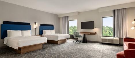 Habitación de hotel con dos camas, un escritorio, una silla y un televisor.