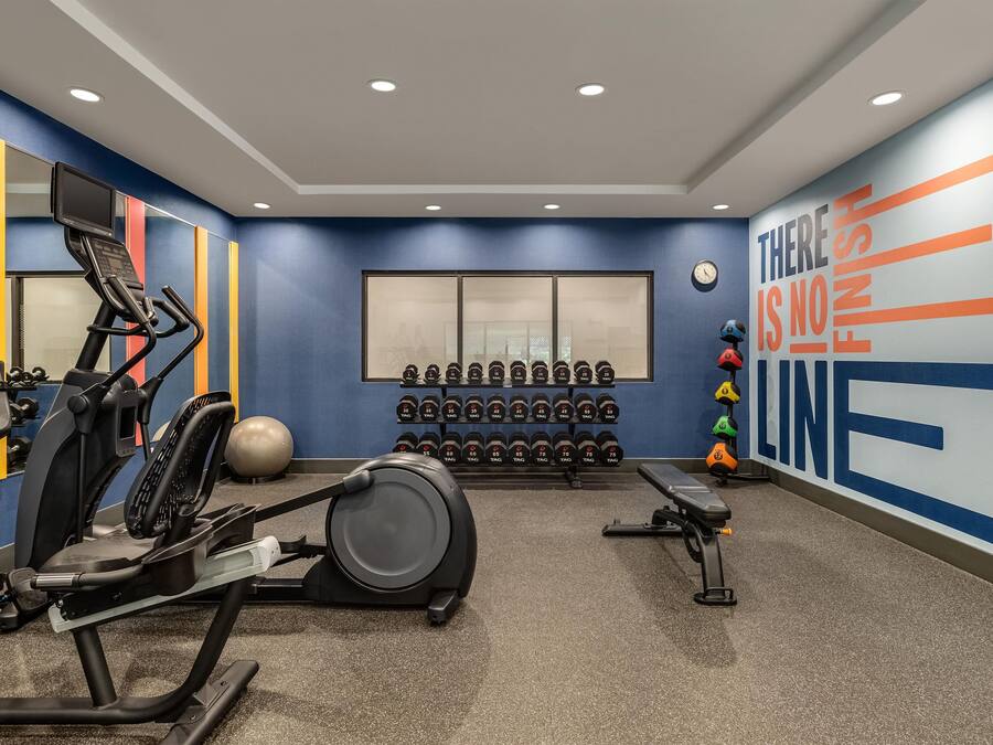A gym with exercise equipment, dumbbells, and a motivational wall.