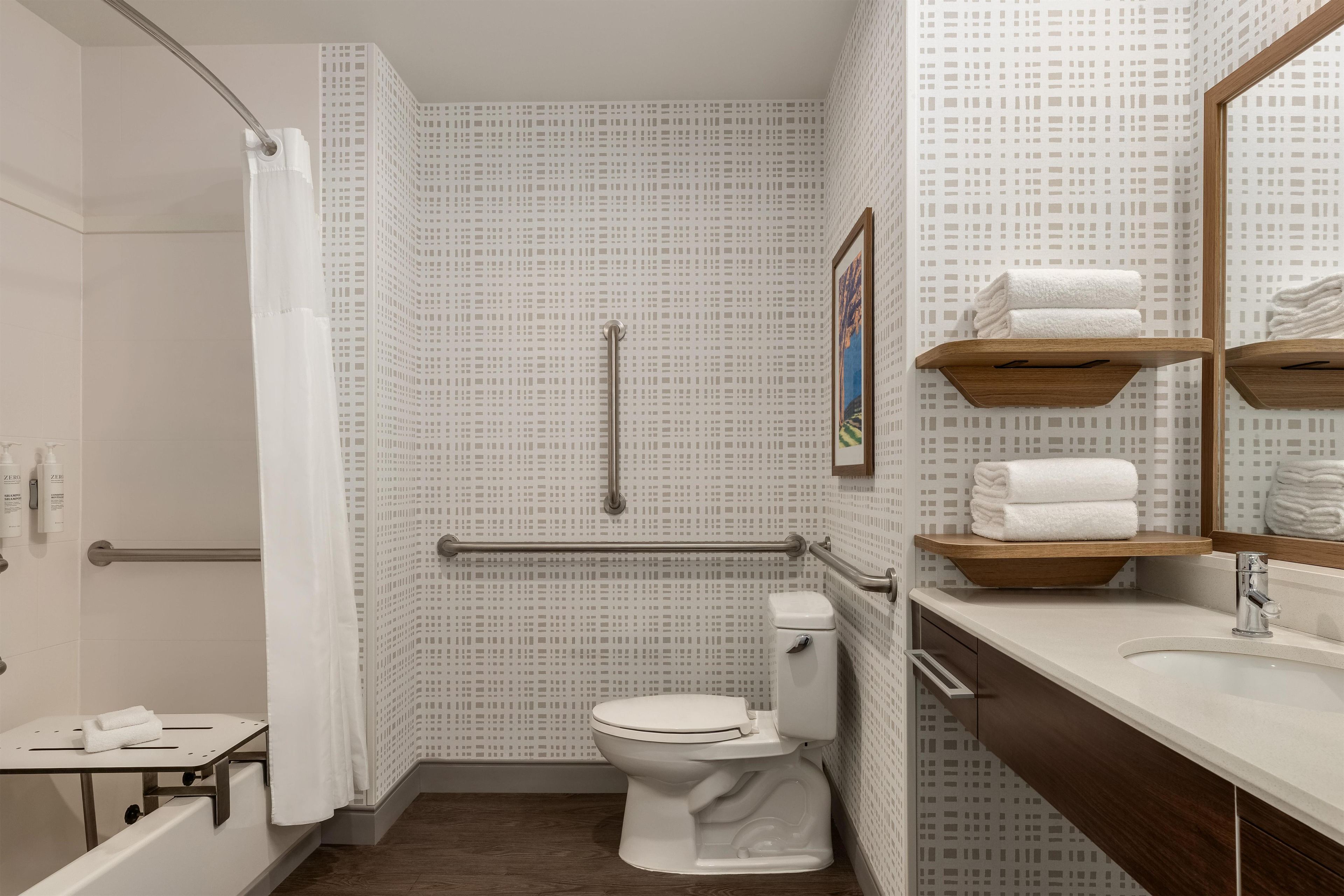 Un baño con inodoro, zona de ducha y lavamanos con espejo.