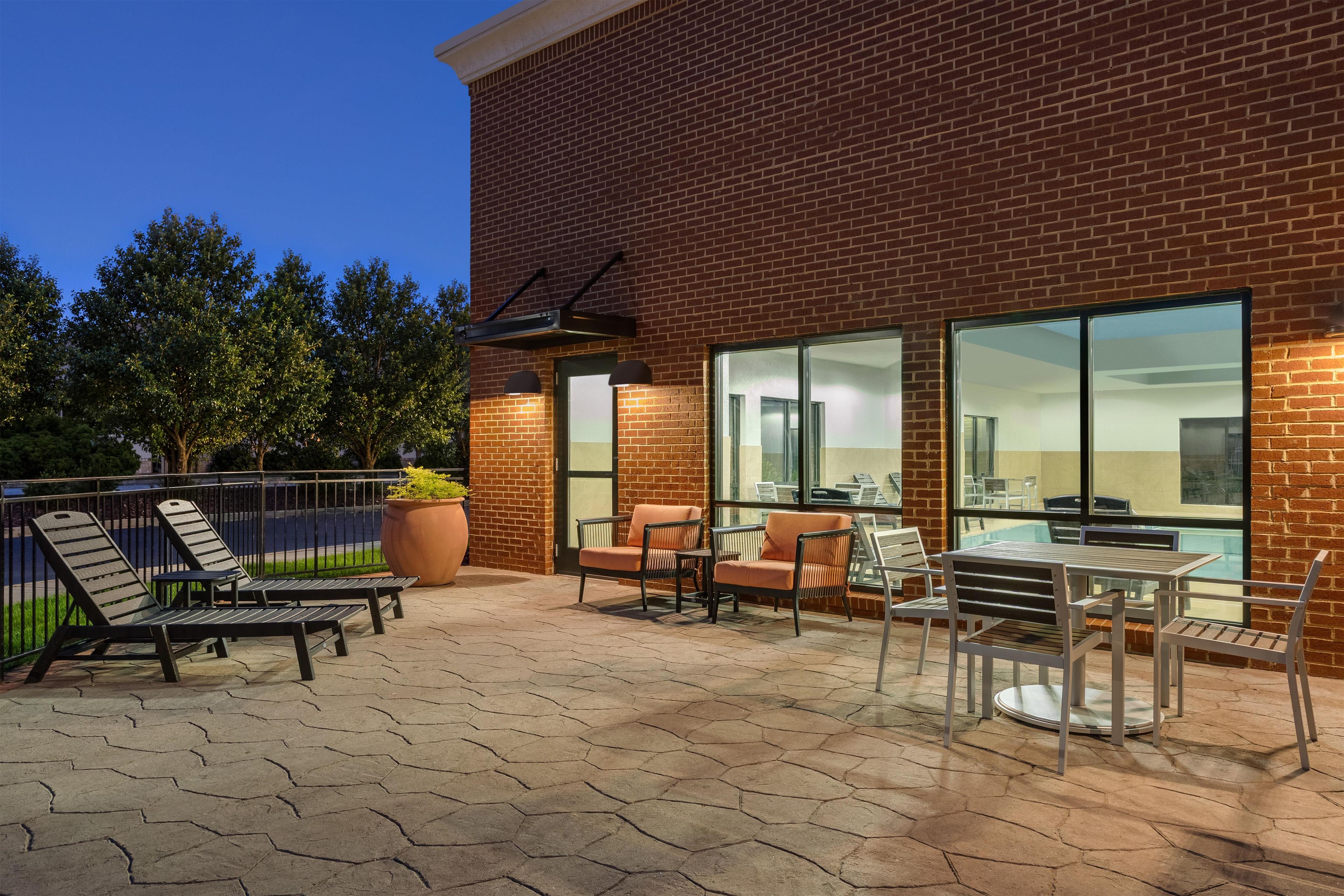 A brick building with a patio area featuring outdoor furniture and a large window.