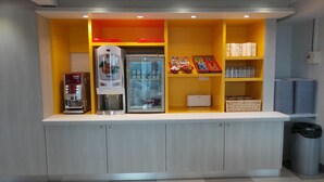 A kitchenette with a coffee machine, a refrigerator, and shelves with cups and condiments. - Premiere Classe Amiens (Amiens)