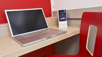 Un ordinateur portable sur un bureau en bois, avec une chaise rouge.