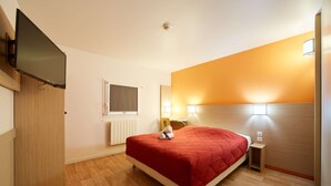 A hotel room with a bed, a TV mounted on the wall, a wooden wardrobe, a bedside table with a lamp, and a window with blinds. - Premiere Classe Amiens (Amiens)