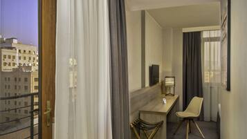 Habitació d'hotel amb balcó, escriptori, cadira i llit.