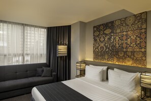 A modern hotel room with a large bed, a sofa, and a decorative wall panel. - Republica Hotel Yerevan (Yerevan)