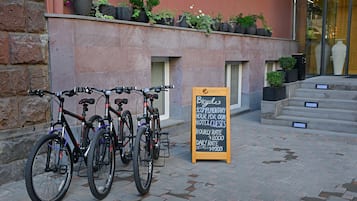 Des vélos sont garés devant un immeuble, et une enseigne annonce un service de location de vélos gratuit pour les clients de l’hôtel.