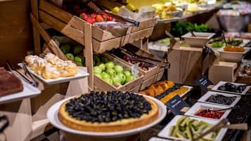 Um buffet com diversos alimentos, incluindo frutas, vegetais e sobremesas.
