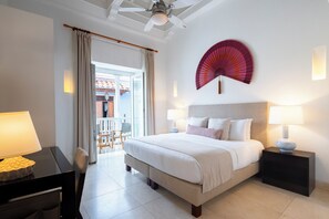 A hotel room with a bed, bedside lamps, a fan, and a view of the outside. - Casa La Cartujita (Cartagena)