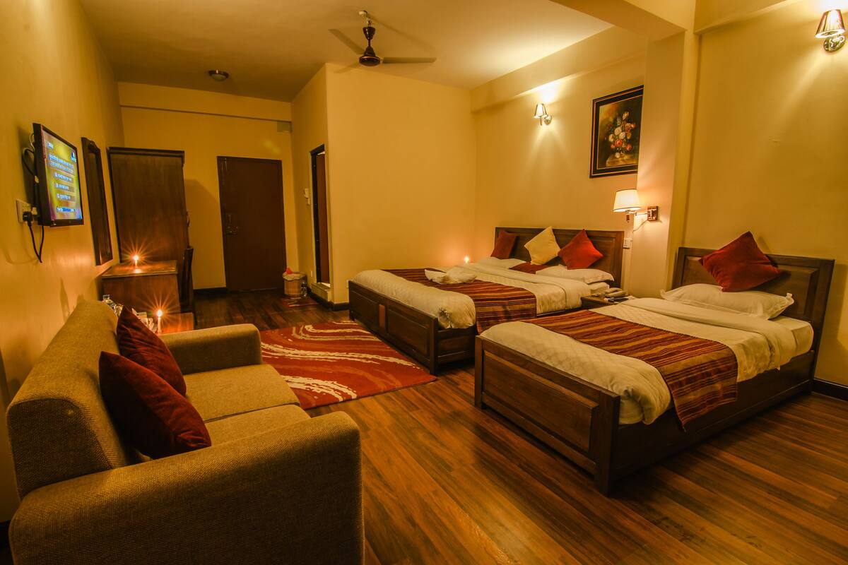 A hotel room with two beds, a sofa, and a TV.