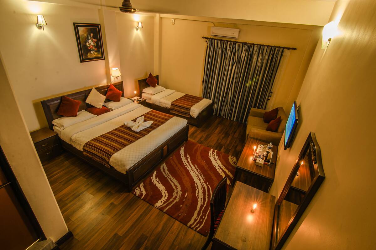 A hotel room with two beds, a desk, and a TV.