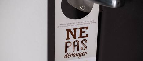 Une porte avec une pancarte indiquant « NE PAS DÉRANGER » et le logo d’un hôtel-restaurant.
