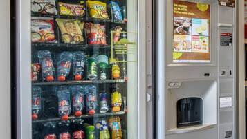 Máquina expendedora llena de refrigerios y bebidas, incluyendo marcas como Twix y Sprite.