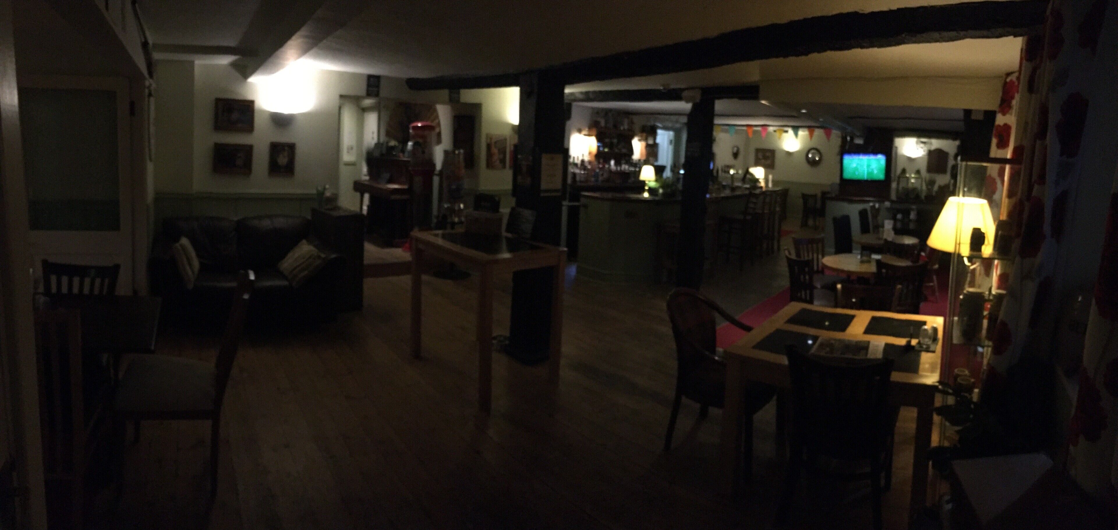 Una stanza scarsamente illuminata con un'area bar, un tavolo da pranzo e un divano.