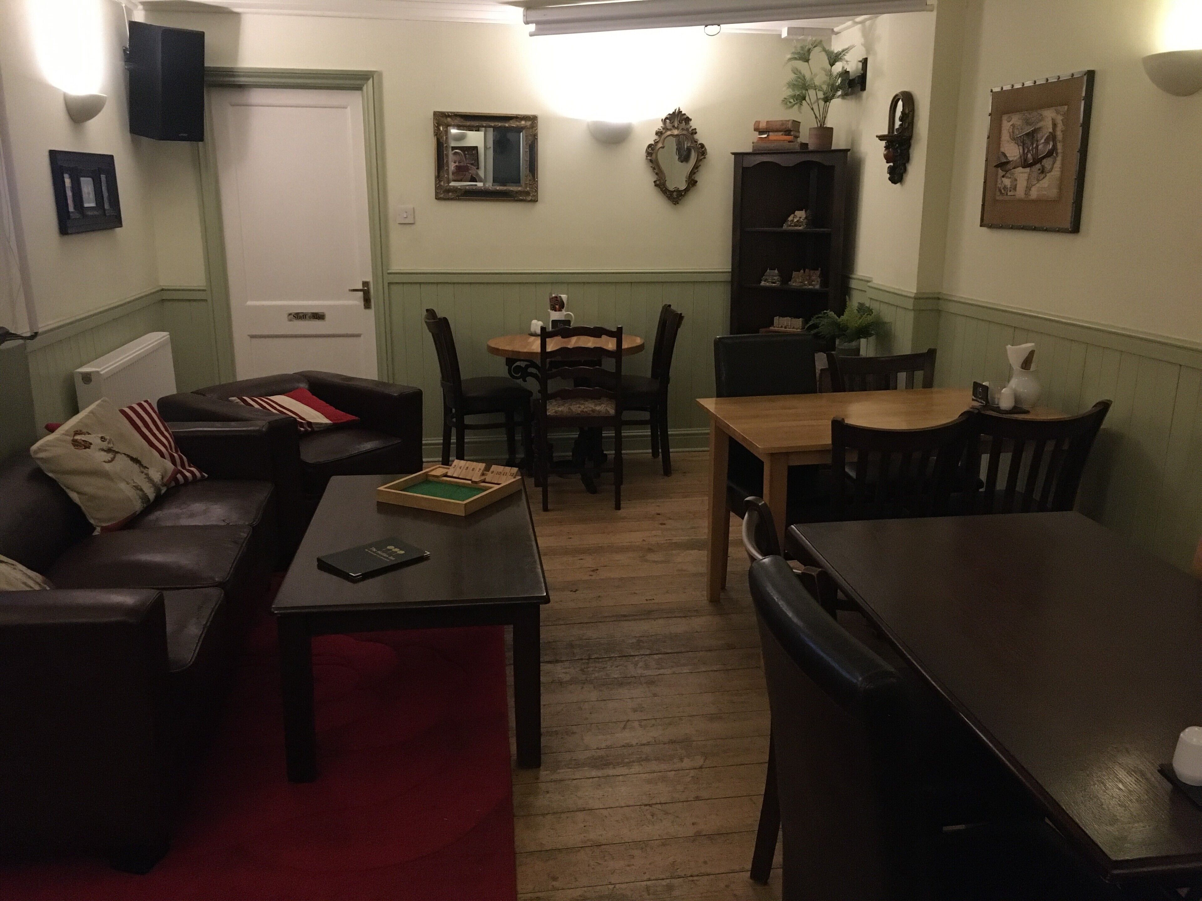 A cozy living room with a sofa, a coffee table, a dining table with chairs, and a bookshelf.