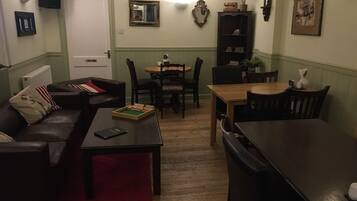 Una sala de estar acogedora con sofá, una mesa de centro, una mesa de comedor con sillas y una estantería.