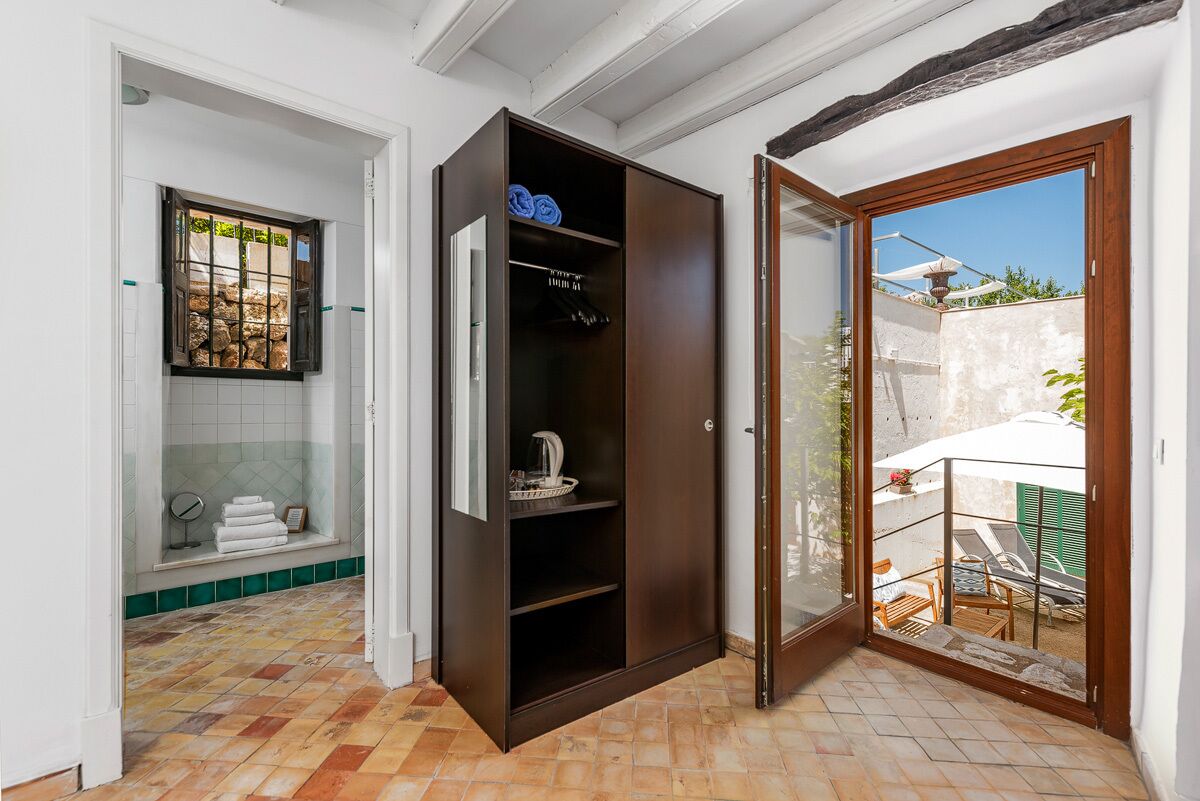 A compact bathroom with a shower, a built-in wardrobe, and a small window with a view of the outside.
