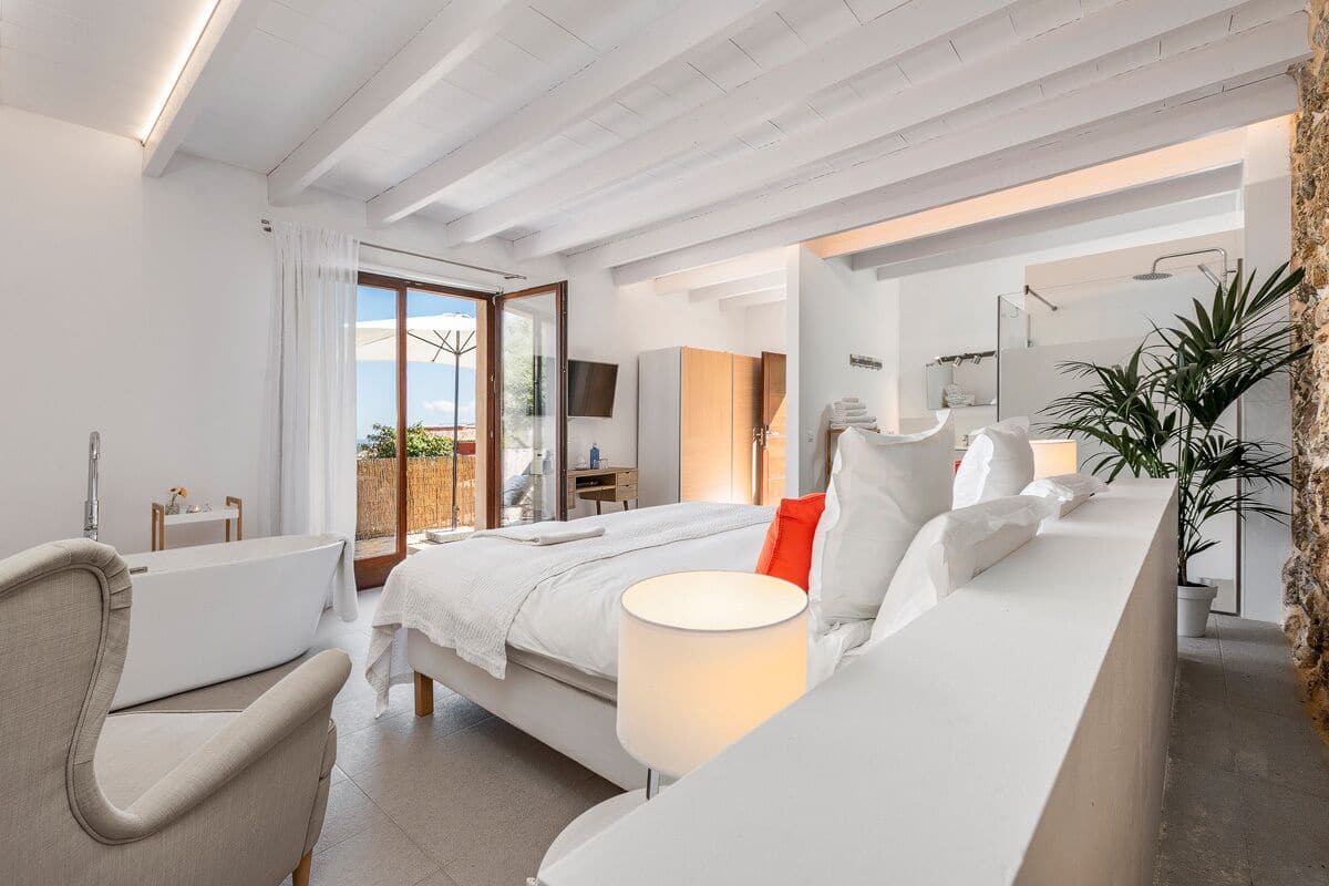 A modern bedroom with a bed, bedside table, and a view of the outdoors.