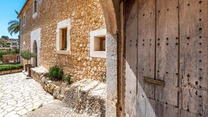 A stone building with arched windows and a wooden door. -  Finca Son Arnau (Selva)