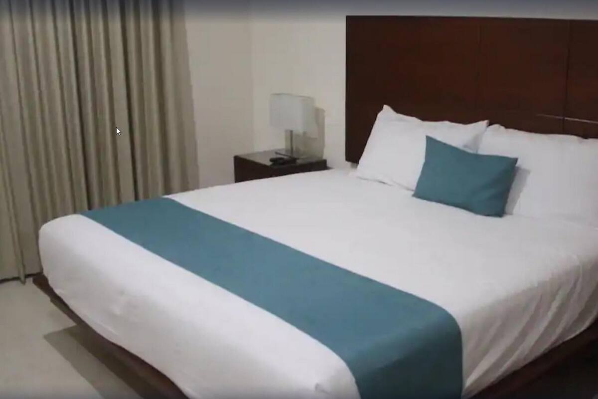A hotel room with a large bed, a nightstand with a lamp, and a wooden headboard.