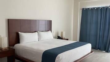 A neatly made bed with a wooden headboard, a bedside table with a lamp, and a ceiling fan.