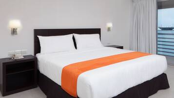 A hotel room with a bed, nightstands, a telephone, and a view of the outside.