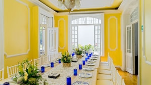 A long dining table set with blue glassware, white plates, and floral centerpieces in a room with yellow walls and white trim. - Hotel Casa González (Mexico City)