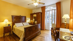 A hotel room with a wooden bed, a desk with a lamp, a wardrobe, and a ceiling fan. - Hotel Casa González (Mexico City)